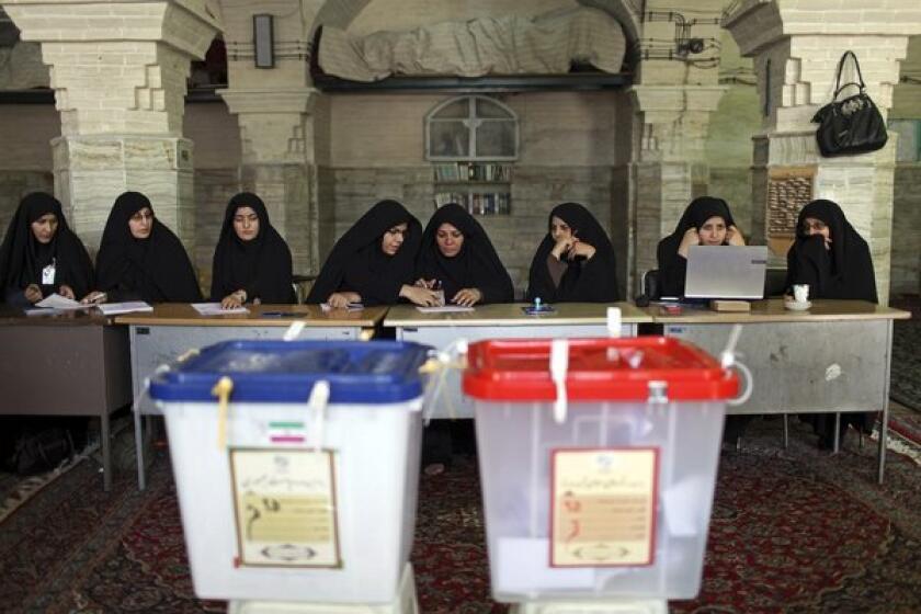 Iranian election workers await voters Friday at a polling station in Qom.