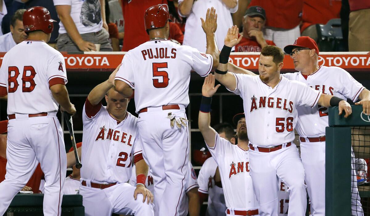 Los Angeles Angels' Albert Pujols, center, is greeted by teammates after he scored on a single hit by David Freese during the fourth inning against the Oakland Athletics on Tuesday.