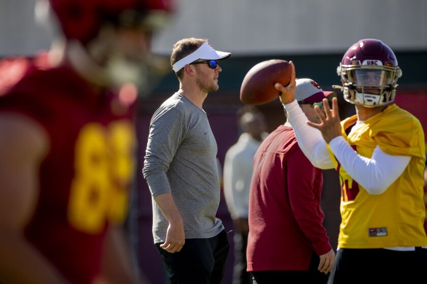USC football coach Lincoln Riley looks watches practice as quarterback Caleb Williams throws a pass 