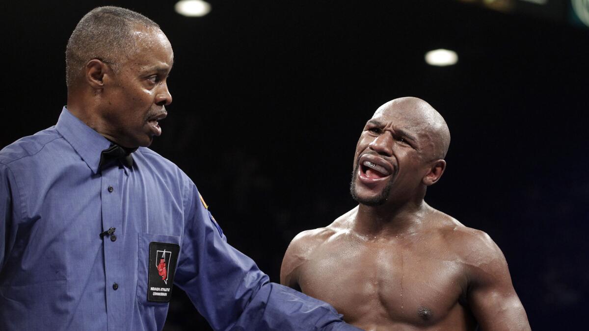 Referee Kenny Bayless holds back Floyd Mayweather Jr. after the boxer accuses Marcos Maidana of a low blow during Mayweather's victory on Sept. 13, 2013.