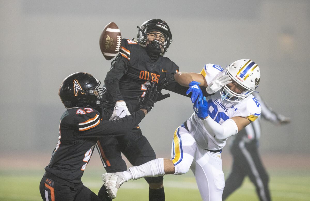 Huntington Beach's Quincy Hankins (43) and AJ Vandermade (4) break up a pass intended for Fountain Valley's Drew Reyes.