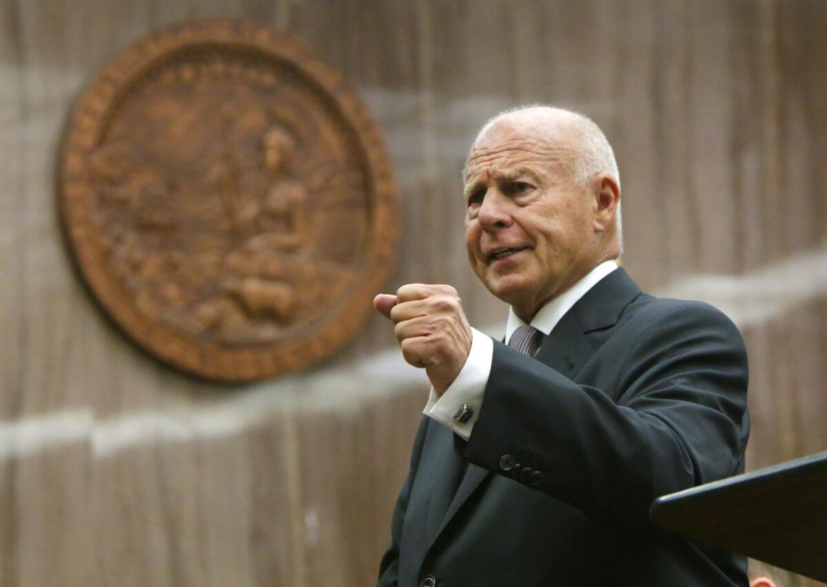 Thomas Girardi in a suit, raising a fist while speaking.