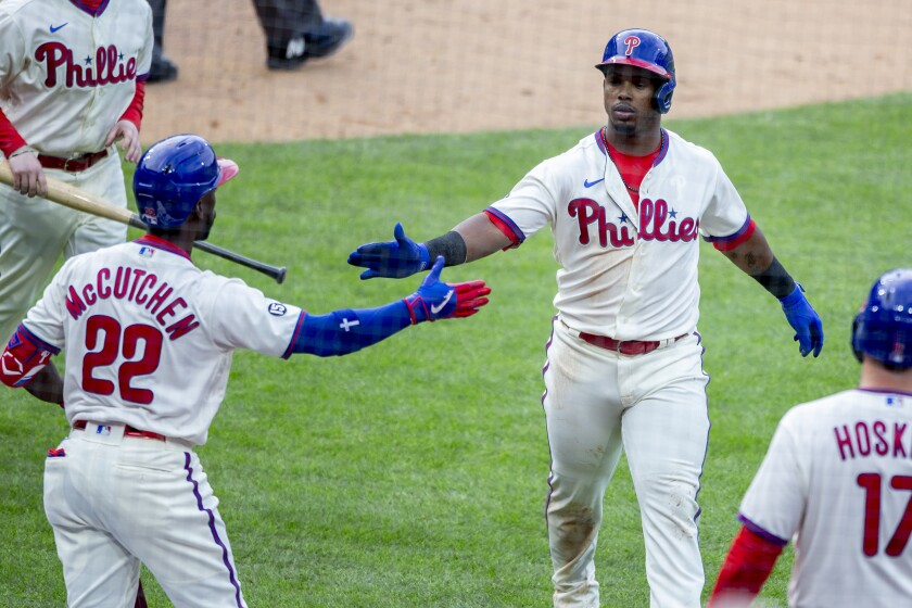 Philadelphia Phillies Jean Segura (2) is congratulated by Andrew McCutchen (22) after scoring on an RBI single by Zack Wheeler (45) during the fifth inning of a baseball game against the Atlanta Braves, Saturday, April 3, 2021, in Philadelphia. (AP Photo/Laurence Kesterson)