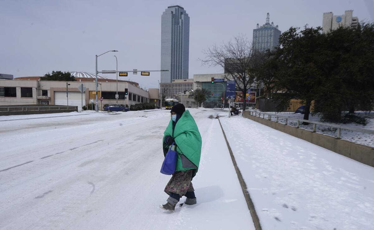 A woman wrapped in a blanket crosses the street near downtown Dallas. 