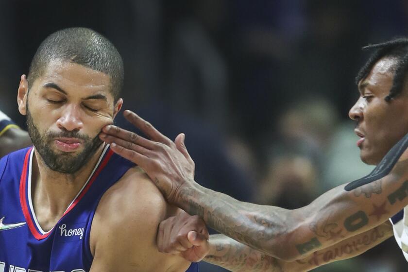 Los Angeles, CA - January 11: Clippers forward Nicolas Batum, center, gets fingers in the face as he drives to the hoop against Nuggets guard Bones Hyland, right, in the first half at Crypto.com Arena in Los Angeles Tuesday, Jan. 11, 2022 i. (Allen J. Schaben / Los Angeles Times)