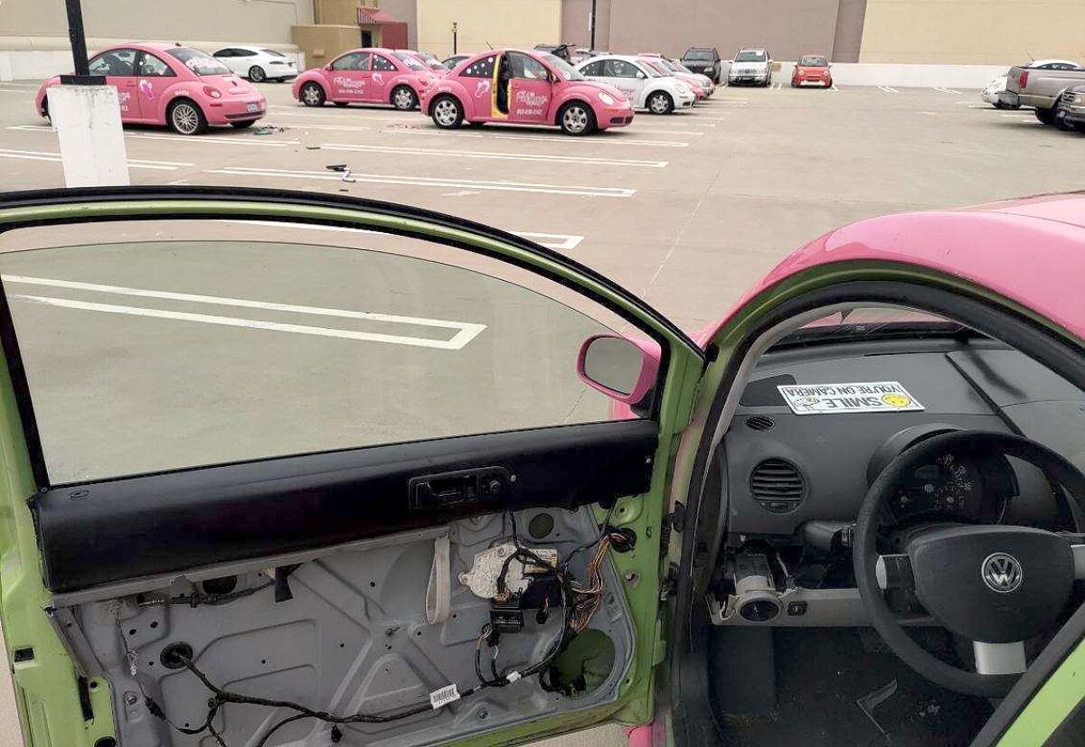 A pink Volkswagen Beetle is shown missing an interior panel on its driver's door.