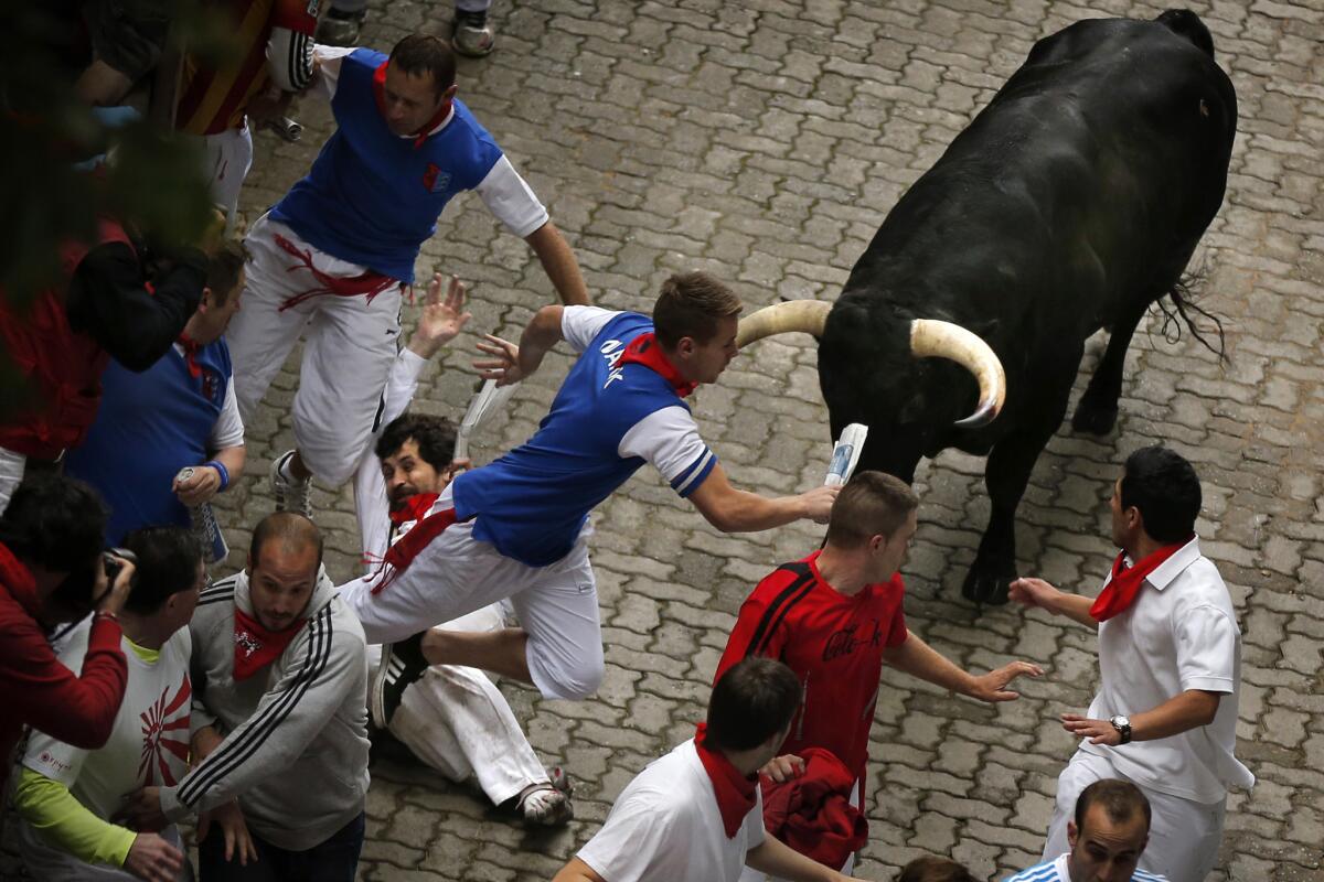 U.S. runner Bill Hillmann, 35, from Chicago, center left, falls seconds before a Spanish bull gored him on his right leg during the running of the bulls in Pamplona.