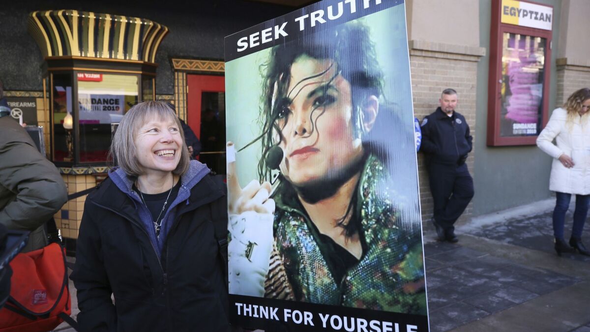 Brenda Jenkyns, who drove from Calgary, Canada, stands with a sign outside the premiere of the "Leaving Neverland" at Sundance.
