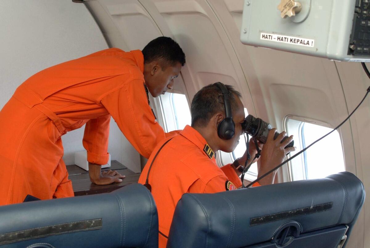 Indonesian air force personnel fly aboard a surveillance aircraft over the Malacca Strait, searching for the missing Malaysia Airlines Flight 370.