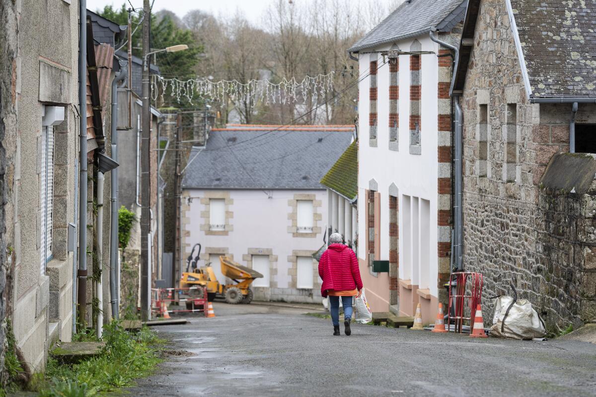 A woman walks down a street in the village of Callac, France