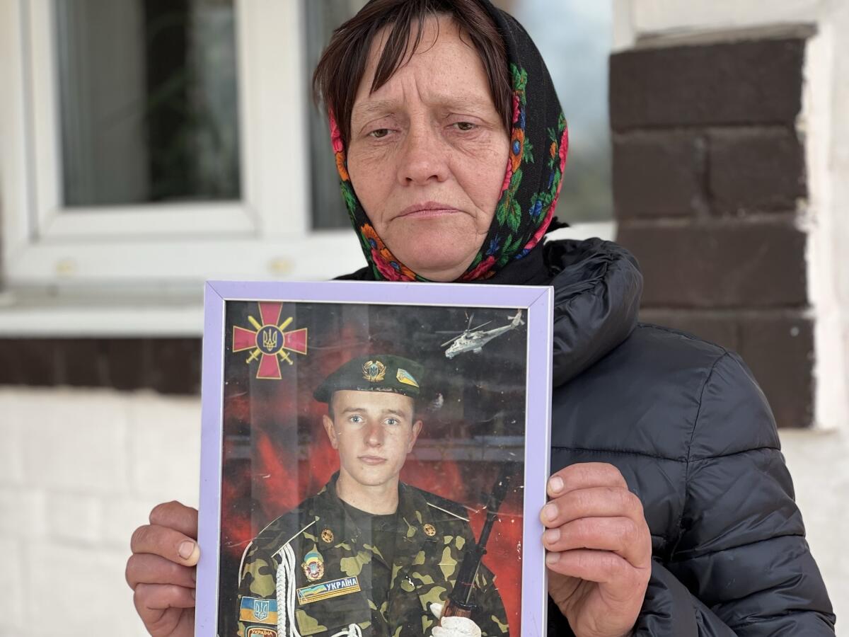 A woman holds a photo of her only son, a 28-year-old soldier killed in the war.