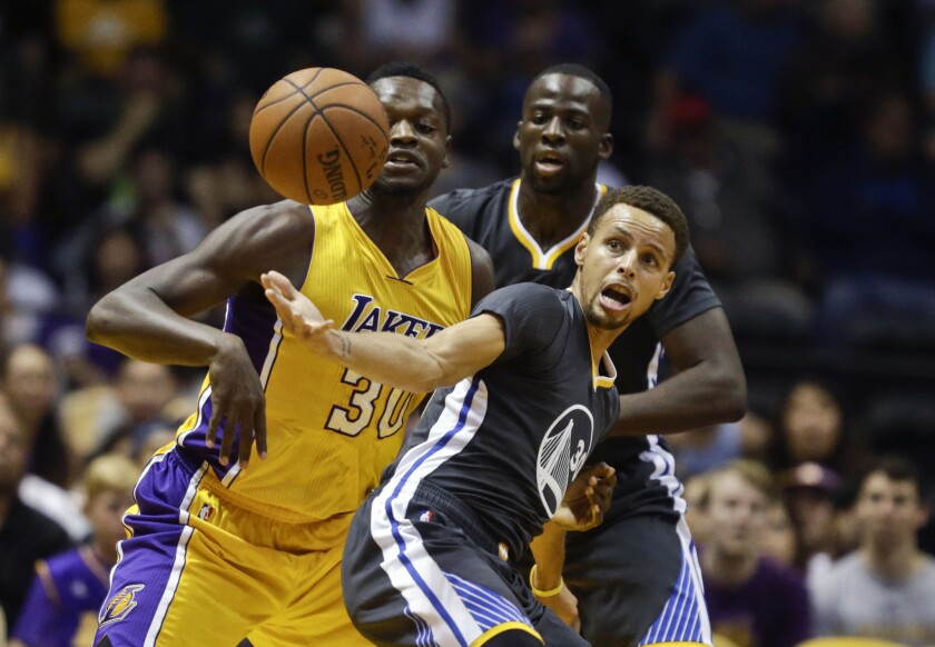 Golden State Warriors guard Stephen Curry battles for a loose ball with Lakers forward Julius Randle during the first half of a preseason game on Oct. 17.