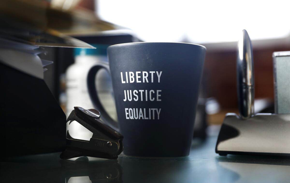 A mug with the words "Liberty, justice, equality" on it on a desk.