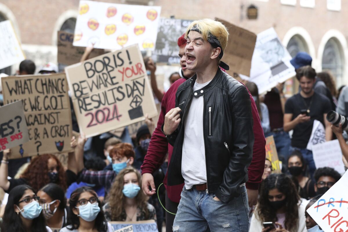 People take part in a protest outside the Department for Education, London, Sunday Aug. 16, 2020, in response to the A-level results. The British government has been urged to “get a grip” over how grades are being awarded to school students, who were unable to take exams earlier this summer because of the coronavirus pandemic. The latest confusion emerged late Saturday when England’s exam regulator launched a review on its own just-published guidance on how students can appeal grades awarded under a complicated system. (Jonathan Brady/PA via AP)