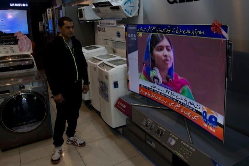 A Pakistani shopkeeper listens to Malala Yousafzai addressing a reception at prime minister house in Islamabad, Pakistan, Thursday, March 29, 2018. Nobel Peace Prize winner Yousafzai returned to Pakistan early Thursday for the first time since she was shot in 2012 by Taliban militants angered at her championing of education for girls. (AP Photo/B.K. Bangash)