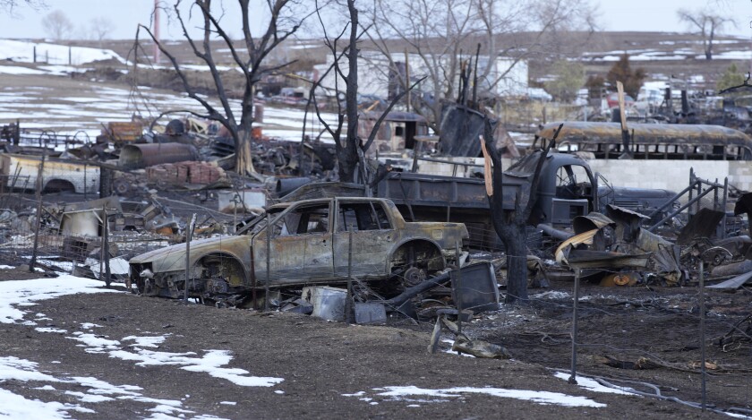 FILE - Charred vehicles sit amid the remains of a home, Jan. 14, 2022, in Superior, Colo., the area being searched for a 91-year-old woman missing since a wildfire burned over 1,000 homes and buildings in suburban Denver last month. Authorities said Wednesday, Jan. 19, 2022, that they have found small bone fragments in their search for Edna Nadine Turnbull but were still investigating whether they were human or not. (AP Photo/David Zalubowski, File)