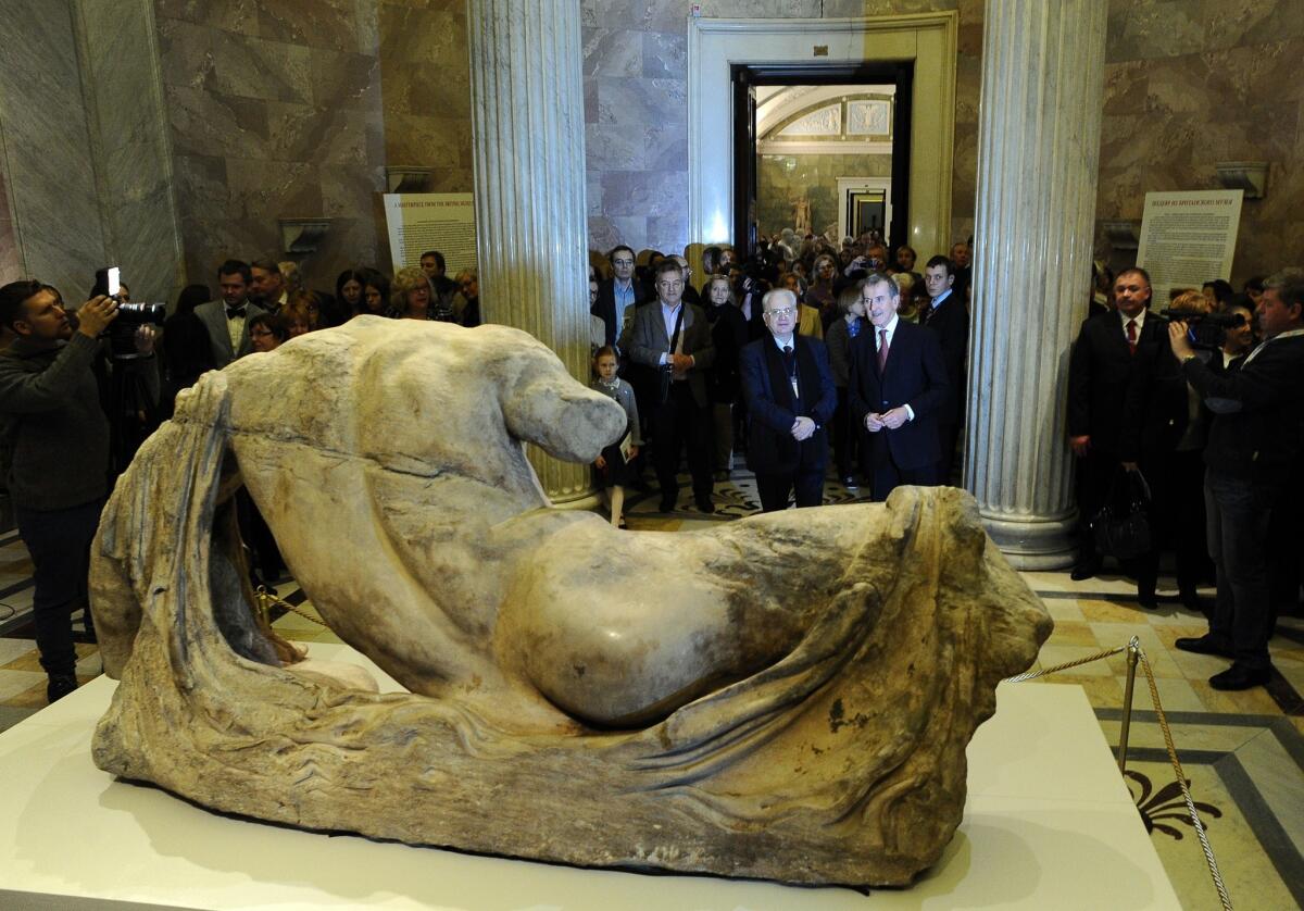 Hermitage Museum director Mikhail Piotrovsky, center, wearing glasses, and British Museum director Neil MacGregor stand in front of a sculpture of the river god Ilissos from the Elgin Marbles that the British Museum is controversially lending to the Russian museum over Greek objections.