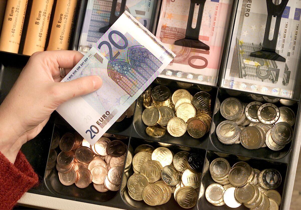 FILE - Euro coins and banknotes are pictured in a shop in Duisburg, Germany, Saturday, Dec. 29, 2001. The European Central Bank said Monday that it plans to redesign its euro banknotes, with a final decision on the new look expected in 2024. The euro was introduced in cash form in 2002, with banknotes based on what the Frankfurt-based central bank for the 19-nation euro area calls an 'ages and styles' theme - with generic windows, doorways and bridges that don't represent any specific place or monument. (AP Photo/Michael Sohn, file)