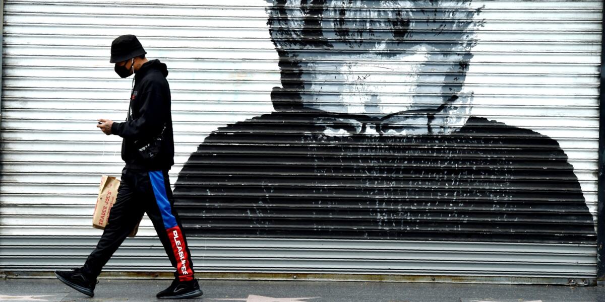 A pedestrian walks past a shuttered storefront March 31 in Los Angeles.