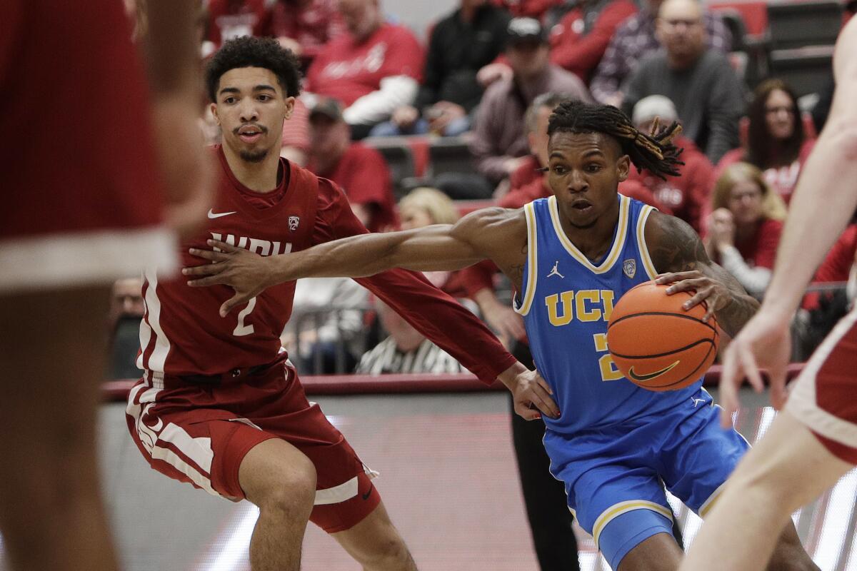 UCLA guard Dylan Andrews, right, drives to the basket under pressure from Washington State guard Myles Rice.