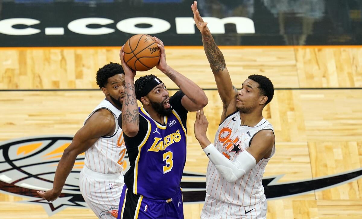 Lakers forward Anthony Davis takes a shot as he gets between Orlando Magic guard Chasson Randle and forward Chuma Okeke.