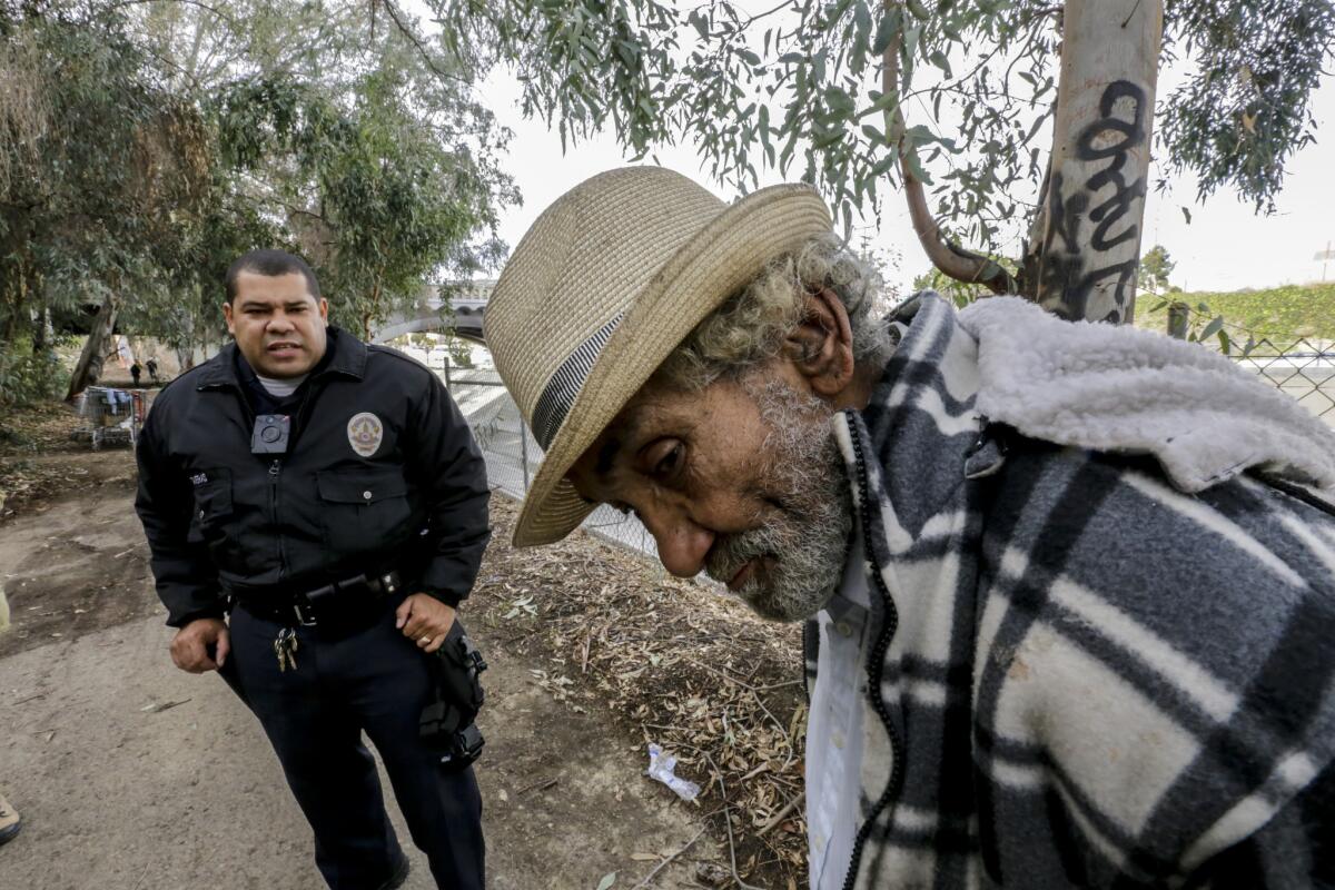 LAPD Officer Ulises Taveras speaks to a man found wandering near a homeless encampment along Arroyo Seco.