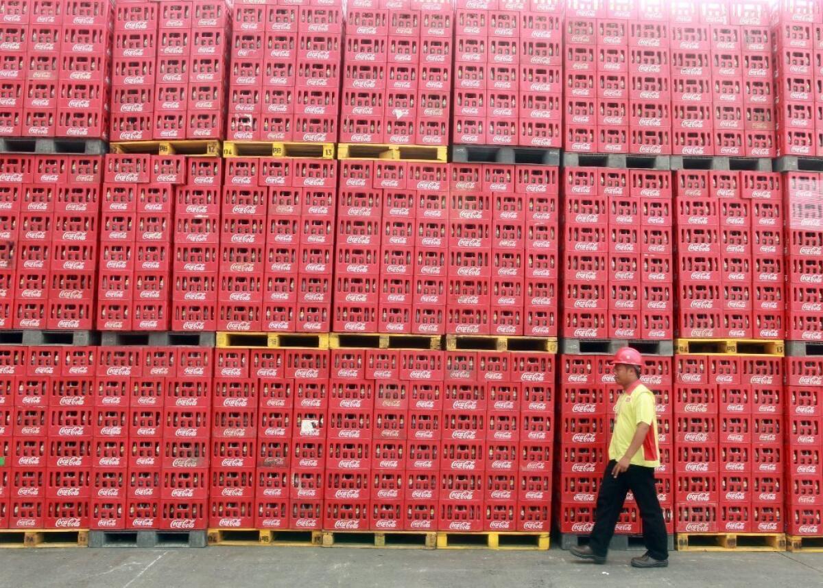 Wherever you go in the world, you'll find Coke: Here a worker strolls past a warehouse supply in Indonesia.