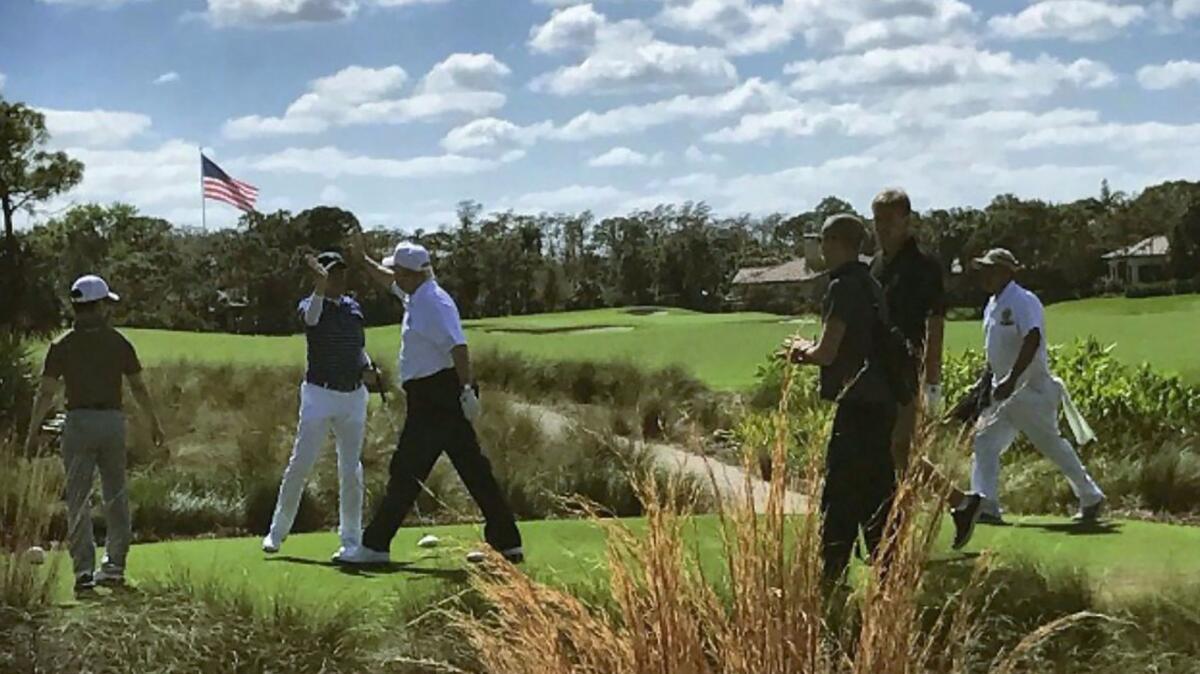 President Trump high-fives Japan's Prime Minister Shinzo Abe while playing golf in Florida on Feb. 11.