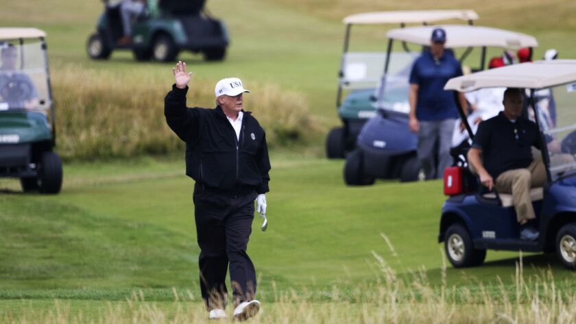 President Trump waves to protesters while playing golf at Turnberry golf club, in Turnberry, Scotland, in July.
