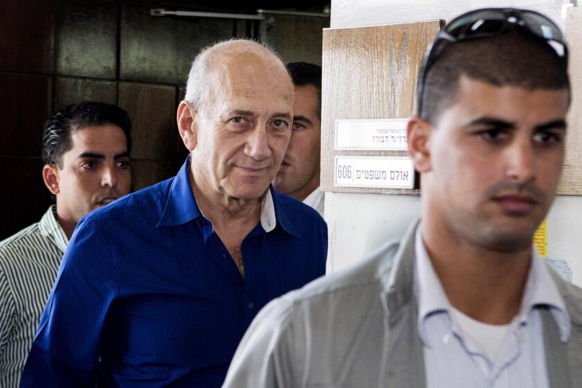 Former Israeli Prime Minister Ehud Olmert, center, leaves Tel Aviv District Court after receiving a prison sentence on a bribery conviction.