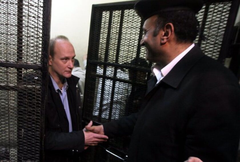 American defendant Robert Becker, left, of the National Democratic Institute shakes hands with a guard in March 2012 during a trial of pro-democracy workers in Cairo.