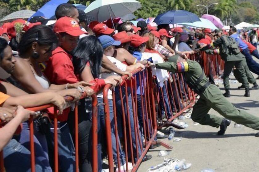 Venezuelan soldiers brace against protective fences as supporters wait in line to pay last respects to the late Venezuelan President Hugo Chavez outside the Military Academy in Caracas.