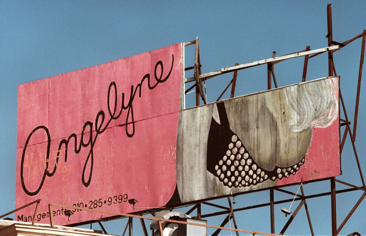A pink billboard with the word Angelyne and an illustration of a woman's breasts.