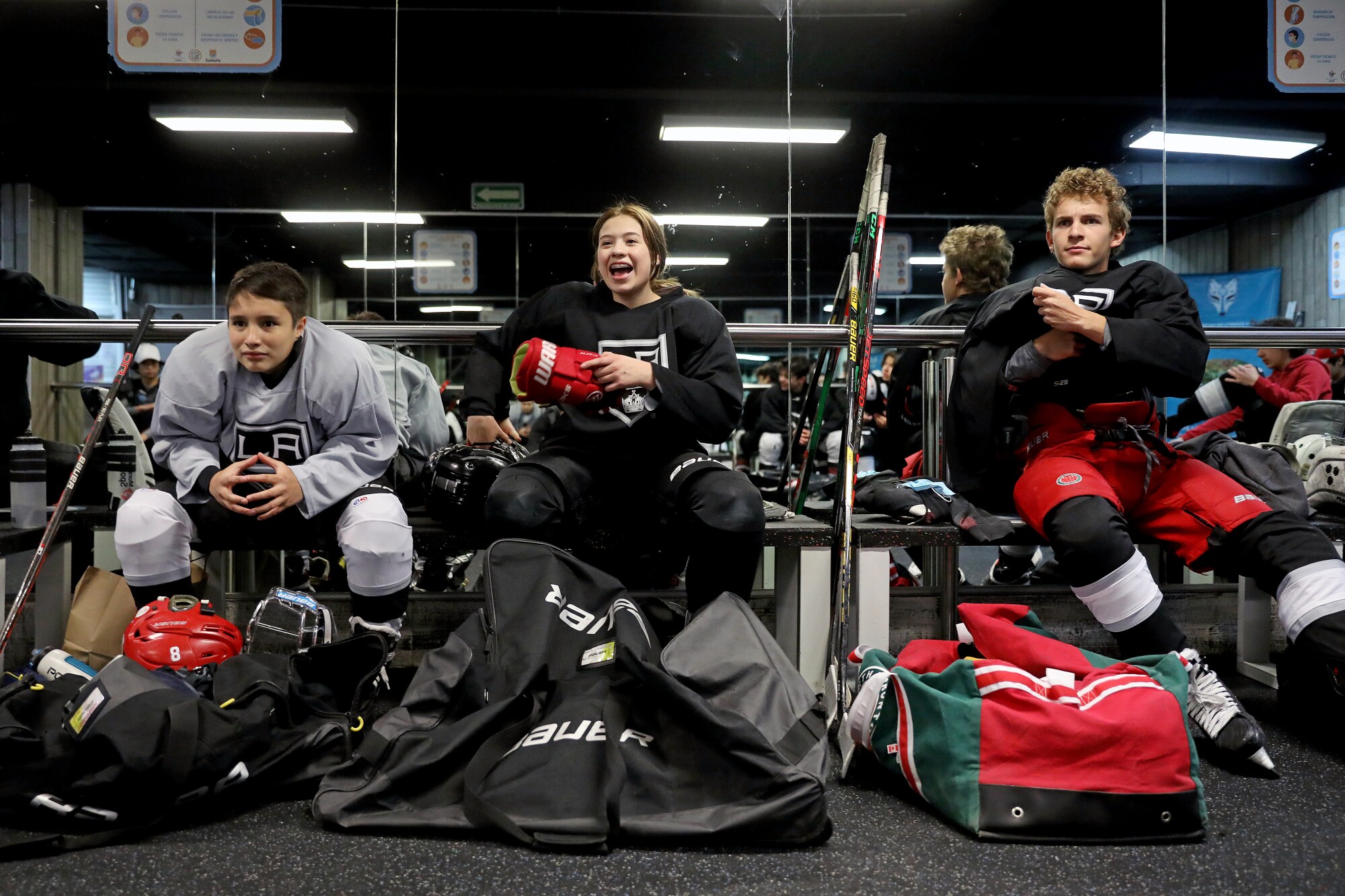 Sebastian Becerril, 13, left, Paula Martínez, center, 15, and Manuel Torres, 16, sit in the locker room before a scrimmage.