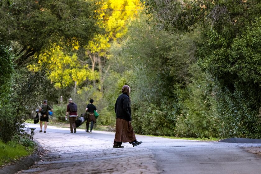 ESCONDIDO, CA - JANUARY 25, 2022: A monk crosses the road as campers head into the park at Deer Park Monastery on January 25, 2022 in Escondido, California. The park is open during the week so people can pay homage to beloved Buddhist monk and teacher That Nhat Hanh, who dies Friday at age 95. He help set up the Escondido monastery 20 years ago.(Gina Ferazzi / Los Angeles Times)