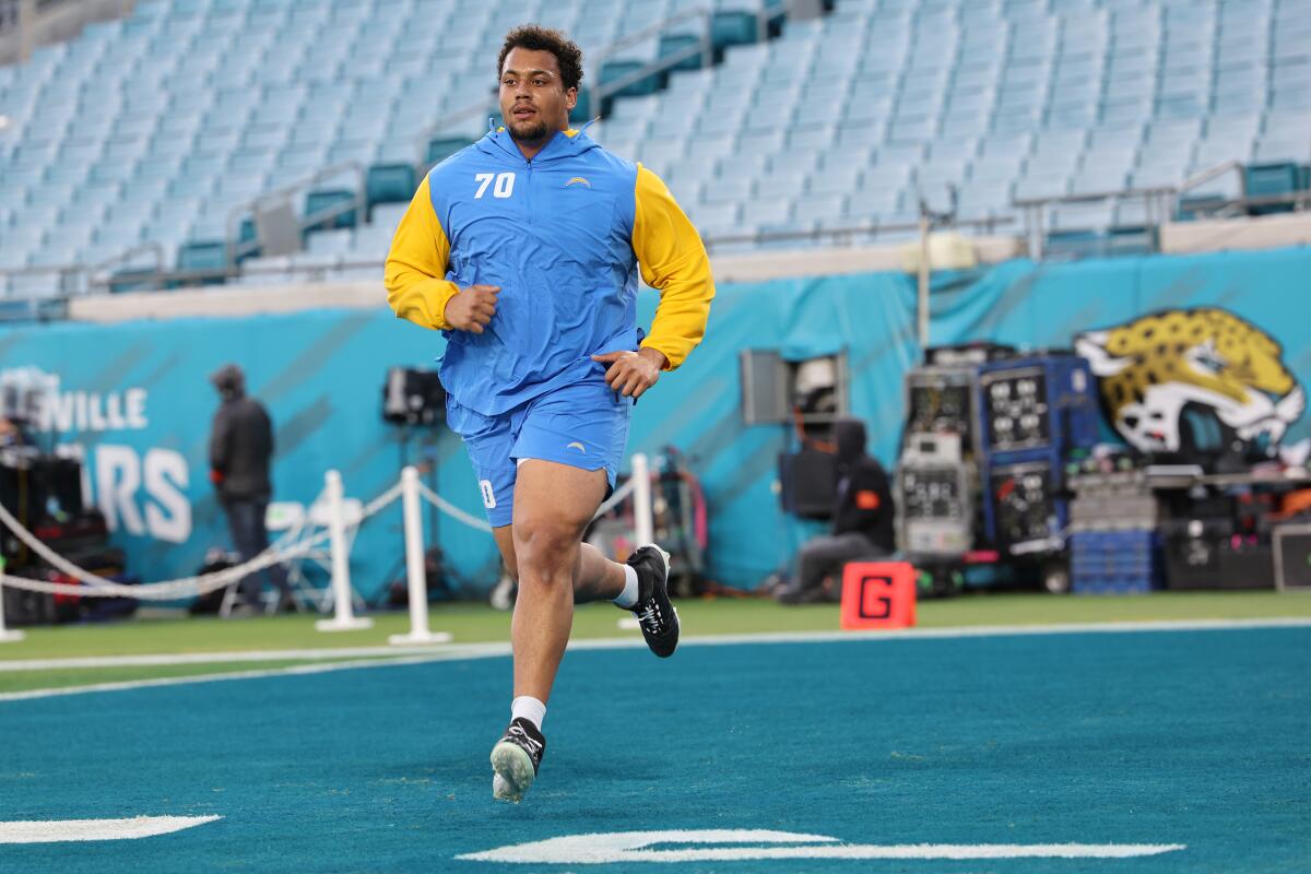 Chargers offensive tackle Rashawn Slater runs across the end zone in shorts.