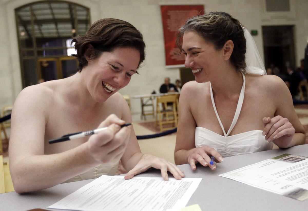 Cynthia Wides, right, and Elizabeth Carey file for a marriage certificate at City Hall in San Francisco on June 29, 2013. A new law will change state code to use gender-neutral terms for marriage.