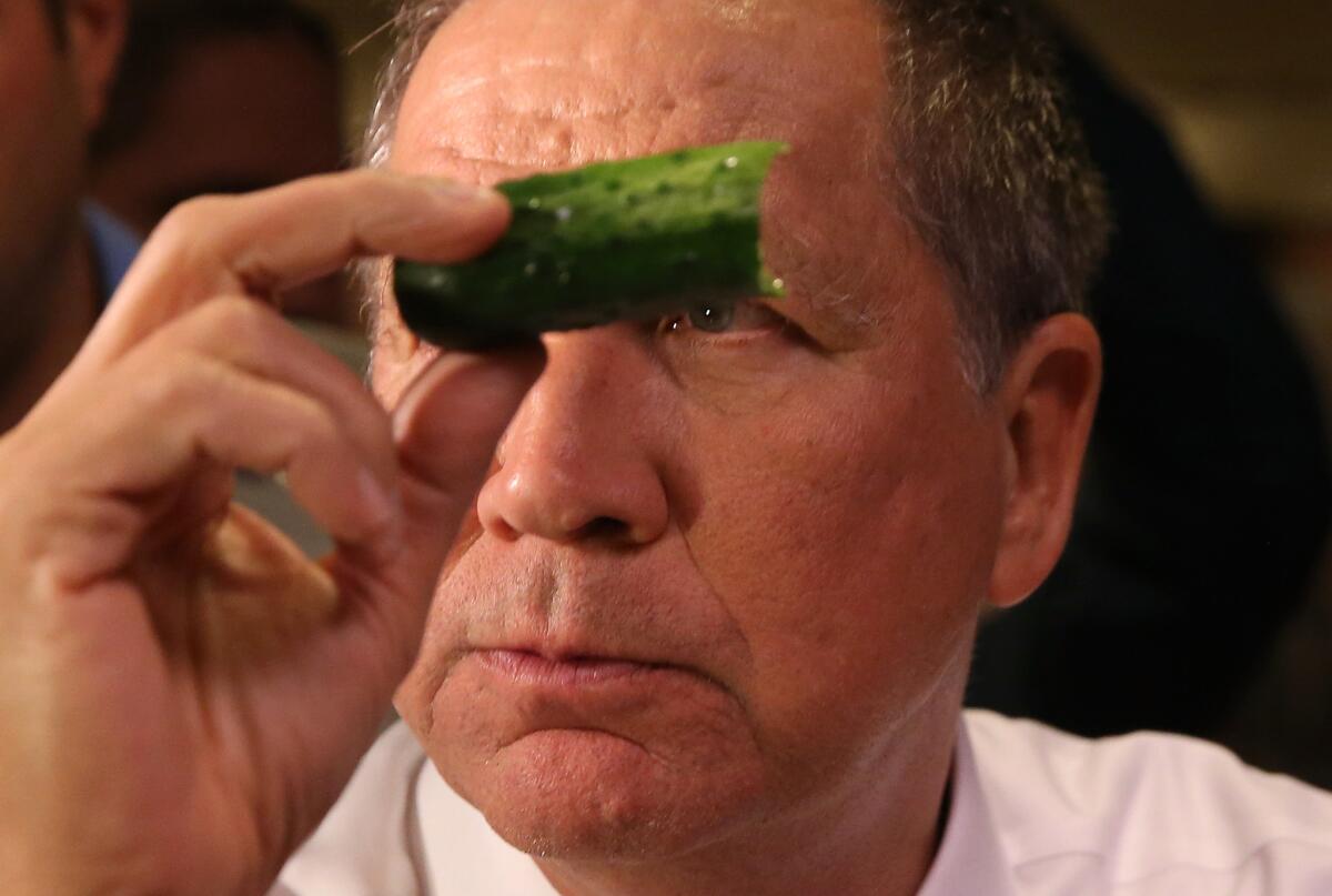 Republican presidential candidate John Kasich wields a pickle at a Lenox Hill deli on Saturday in Manhattan.