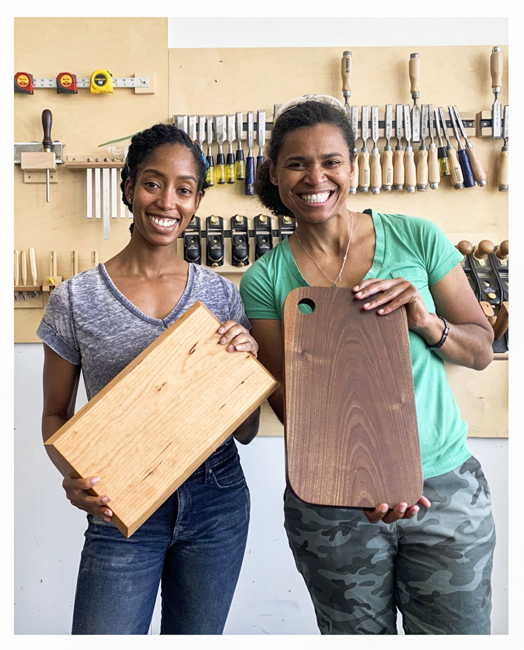 Two women hold pieces of wood at Allied Woodshop 