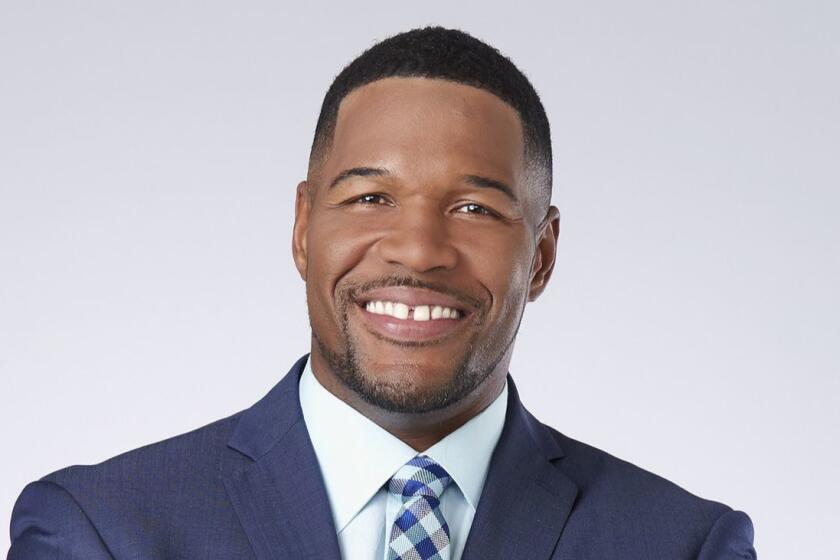 A portrait of Michael Strahan in a blue jacket and checked tie