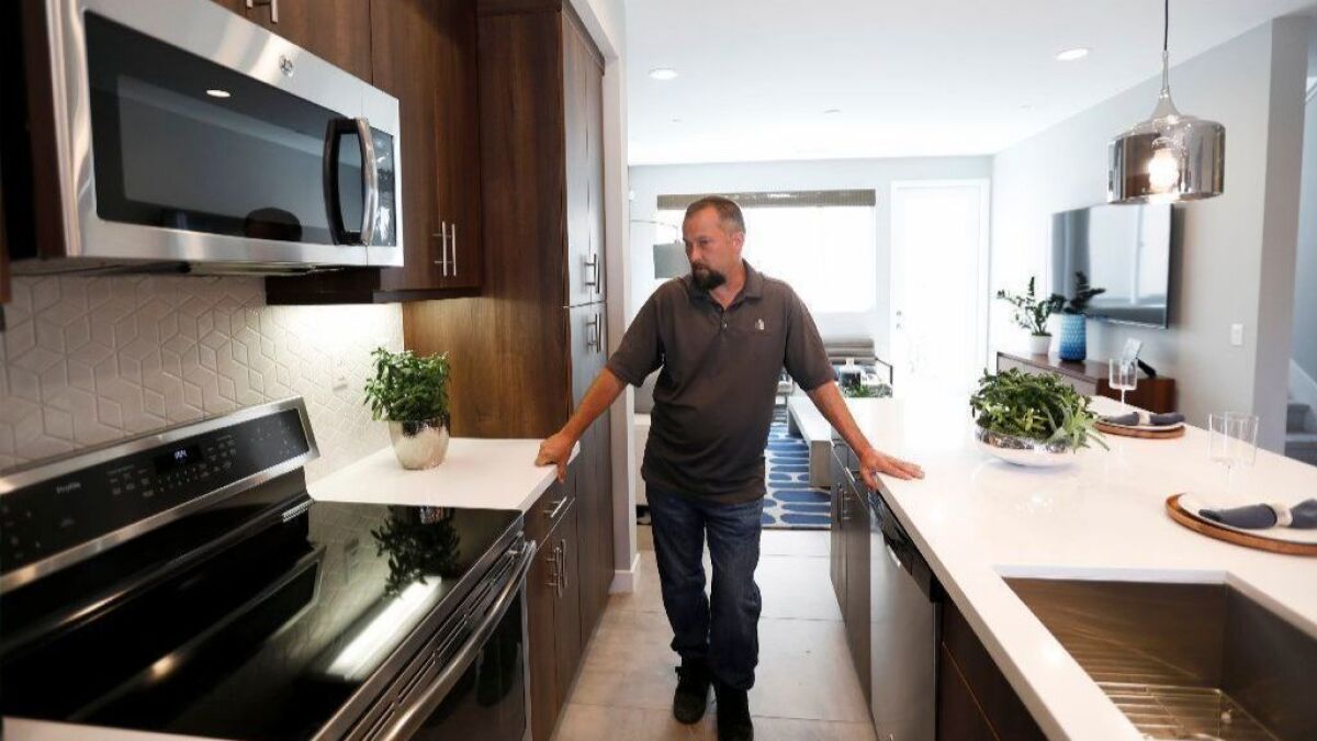 Construction manager Chris Smith shows off an induction cooktop at an all-electric, solar-powered town home development being built by City Ventures in Bellflower, on March 25, 2019.