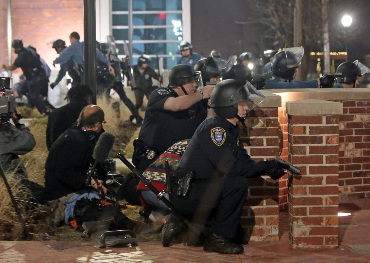 Police take cover after two officers were shot outside the Ferguson Police Department early Thursday after a night of protests.