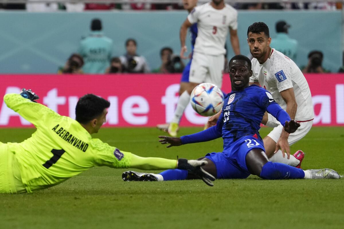 Iran goalkeeper Alireza Beiranvand, left, makes a save in front of U.S. forward Tim Weah in the first half.