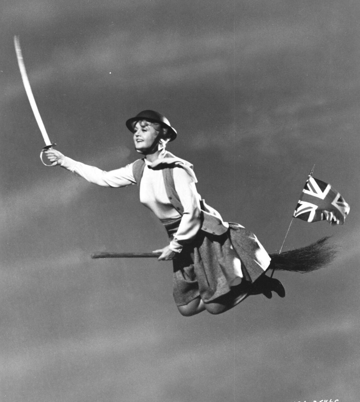 A woman holding a sword and riding a broomstick with a British flag on it