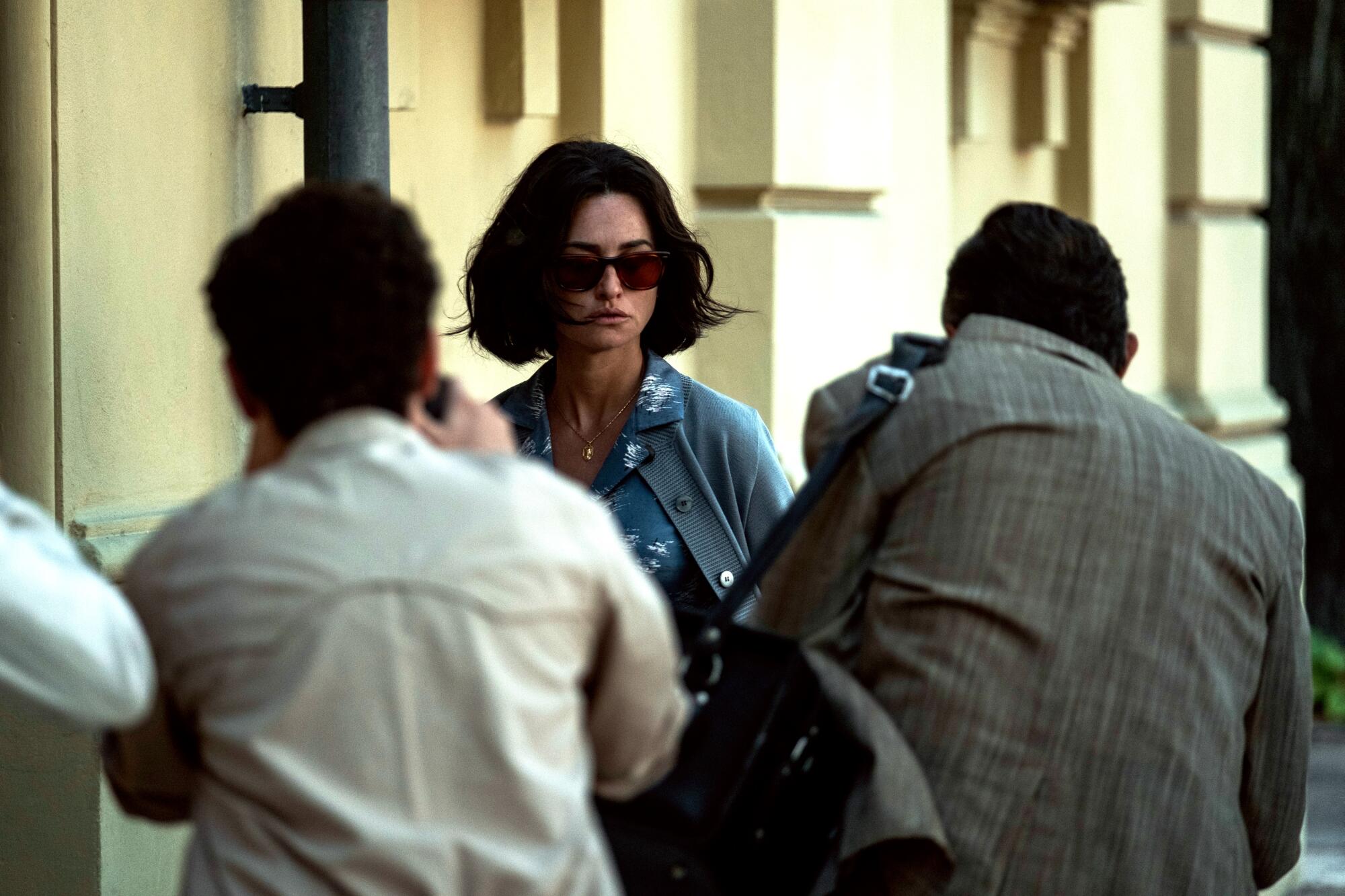 A woman in shades is photographed by paparazzi.