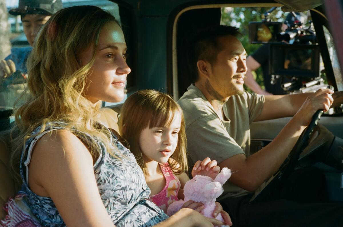 A woman, a little girl and a man sit in a truck.