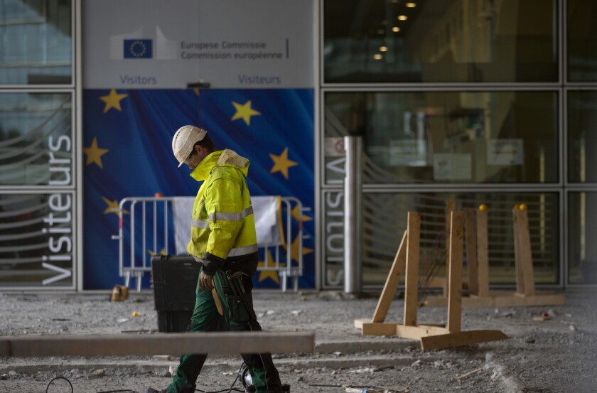 FILE - In this Wednesday, Oct. 9, 2019 file photo, a construction worker stands in front of a door with the EU stars at EU headquarters in Brussels. The Brexit process shook the EU foundations and laid bare the need for much-delayed renovations, but tthe question now is where to start the revamp and who is going to foot the bill. (AP Photo/Virginia Mayo, File)