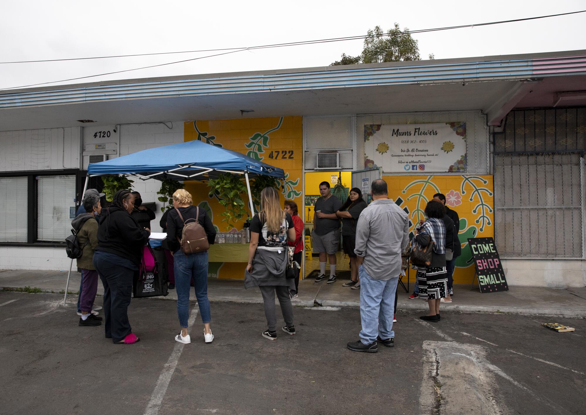 People stand in a parking lot near a covered table