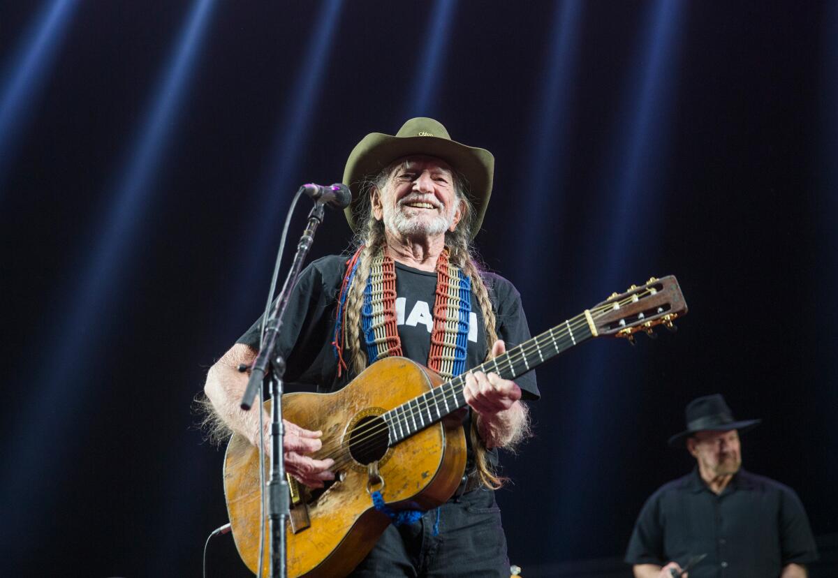 Willie Nelson plays acoustic guitar.