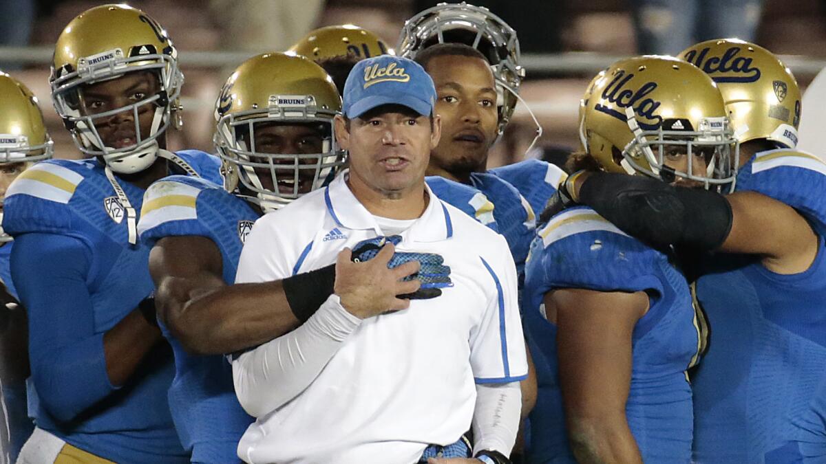 UCLA Coach Jim Mora celebrates with his players during the final seconds of a 38-20 win over USC on Nov. 22.